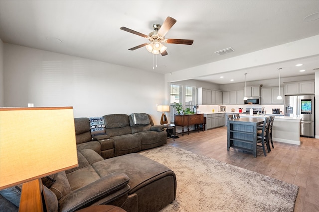 living room with light wood-type flooring and ceiling fan