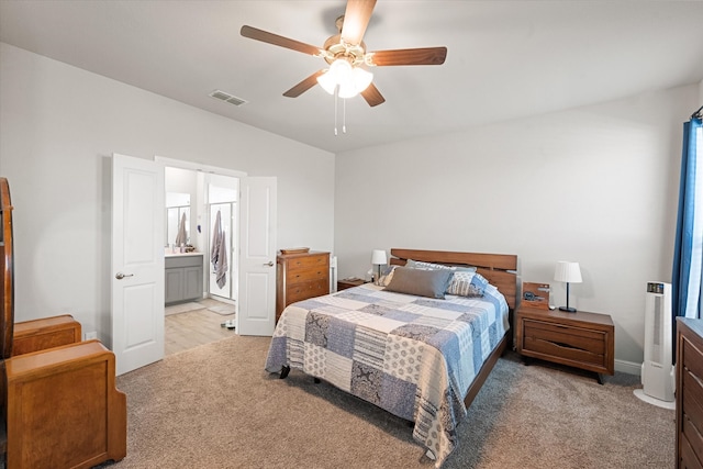 bedroom featuring light carpet, ensuite bathroom, and ceiling fan