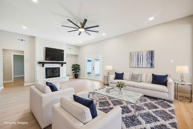 living room featuring light hardwood / wood-style flooring, french doors, a fireplace, and ceiling fan