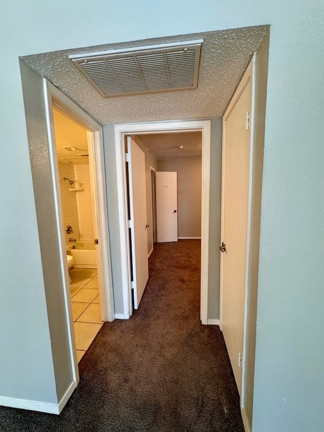 corridor featuring carpet and a textured ceiling