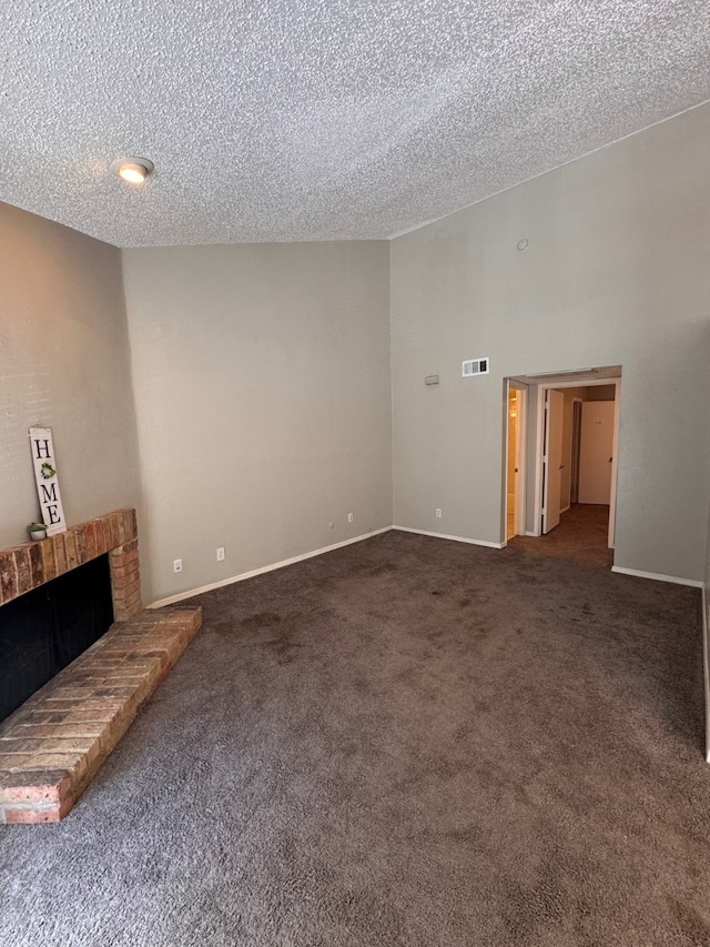 unfurnished living room with a textured ceiling, dark colored carpet, and a fireplace