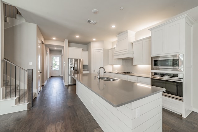 kitchen featuring white cabinets, stainless steel appliances, sink, and an island with sink