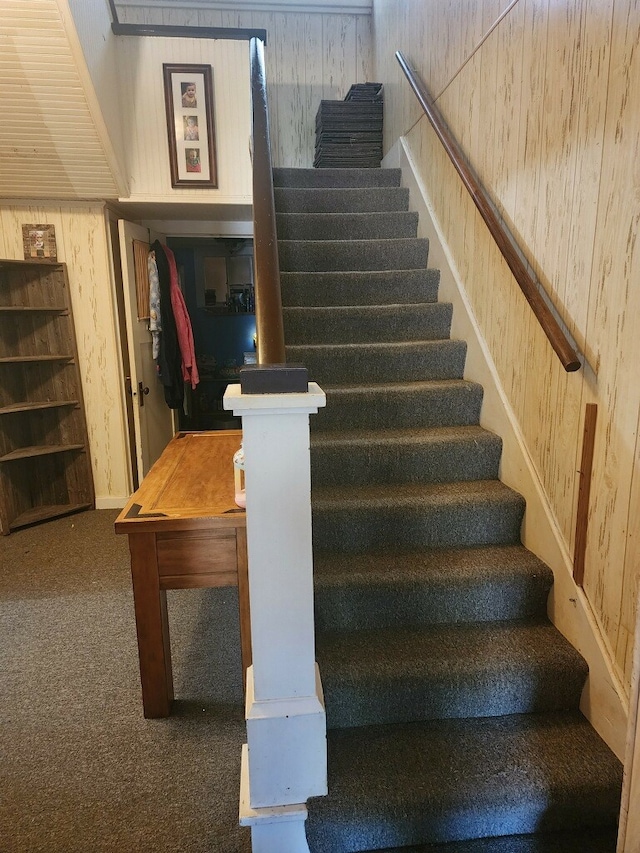 staircase featuring wood walls and carpet