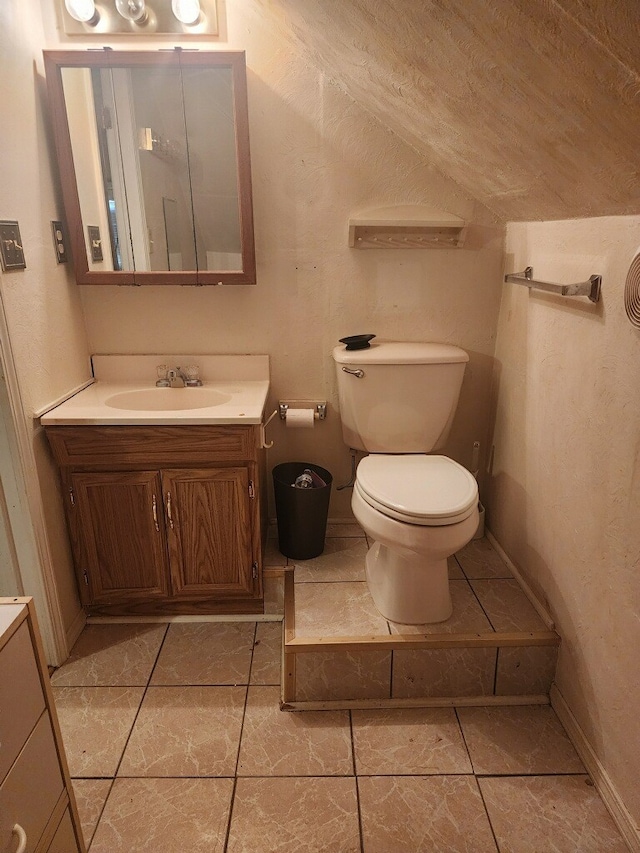 bathroom with vanity, toilet, tile patterned floors, and vaulted ceiling