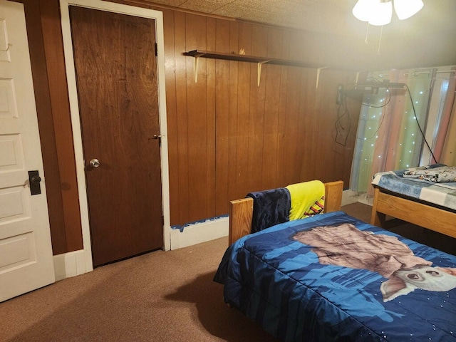 carpeted bedroom with a closet and wooden walls