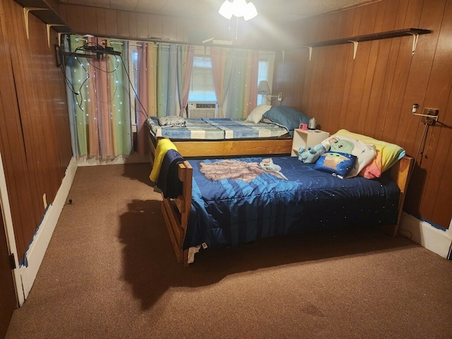 carpeted bedroom featuring cooling unit, wooden walls, and ceiling fan