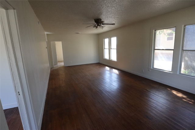 empty room featuring a wealth of natural light, dark wood-type flooring, a textured ceiling, and ceiling fan