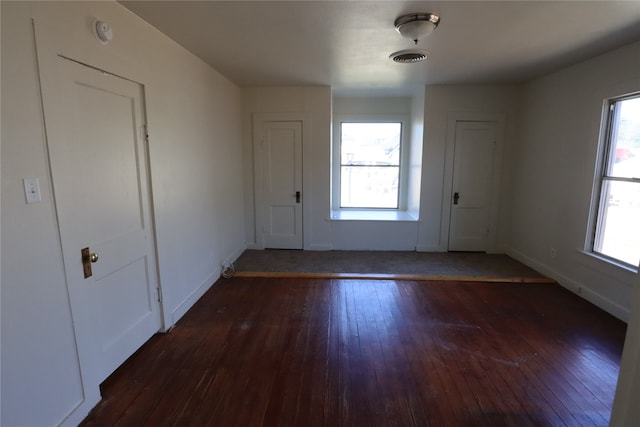 empty room with dark hardwood / wood-style flooring and a wealth of natural light