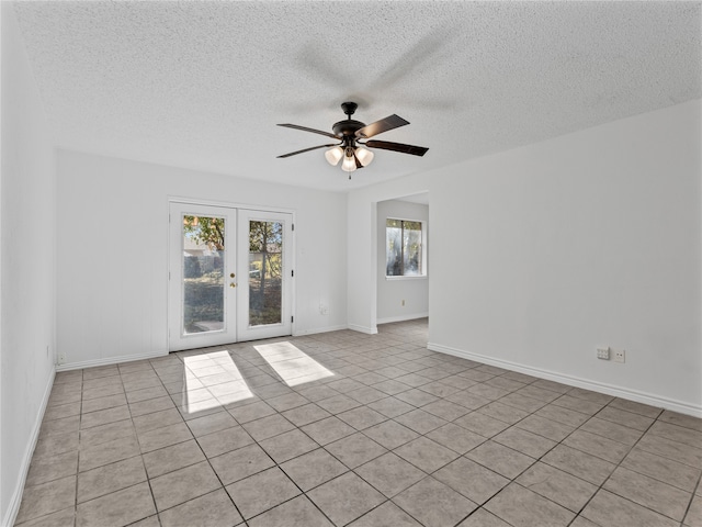 spare room with french doors, a textured ceiling, ceiling fan, wooden walls, and dark tile patterned flooring