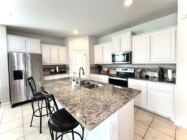 kitchen featuring white cabinets, stainless steel appliances, a center island with sink, and sink