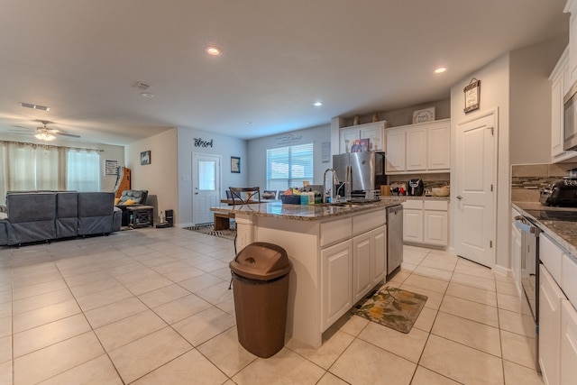 kitchen with a kitchen bar, a kitchen island with sink, and white cabinets