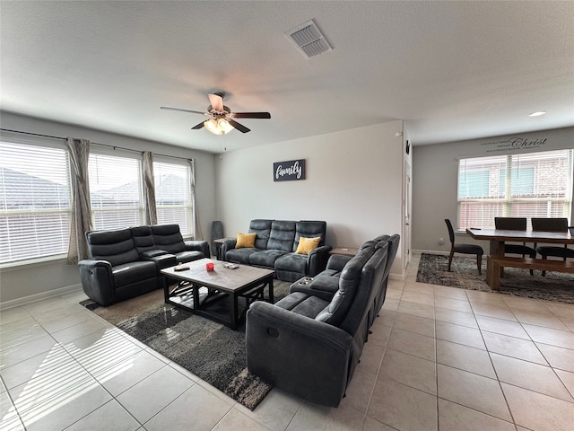 living room with ceiling fan, light tile patterned floors, a textured ceiling, and a wealth of natural light