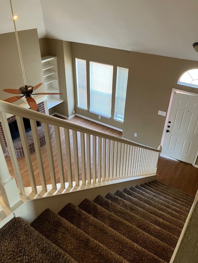 stairway featuring lofted ceiling, wood-type flooring, plenty of natural light, and ceiling fan