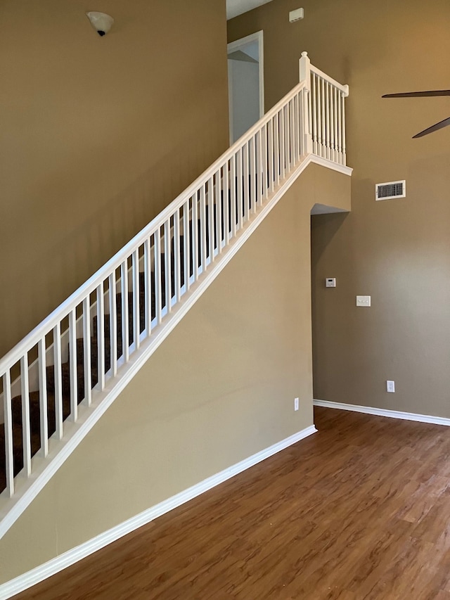 stairs with wood-type flooring and ceiling fan