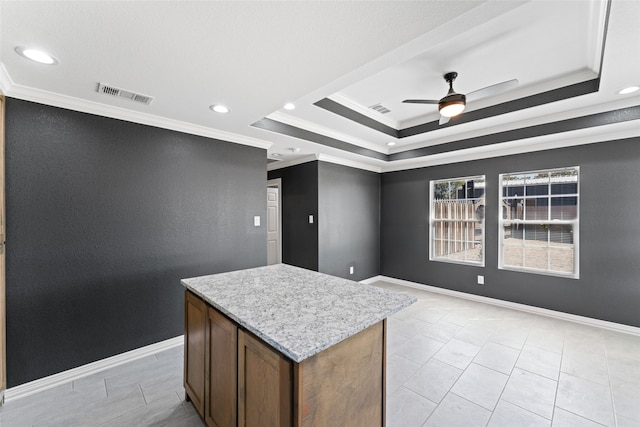 kitchen with ceiling fan, crown molding, a center island, and a raised ceiling