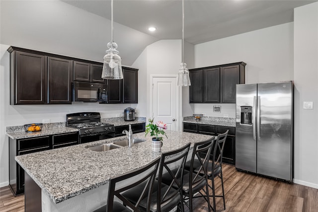 kitchen featuring lofted ceiling, hanging light fixtures, dark hardwood / wood-style floors, black appliances, and sink