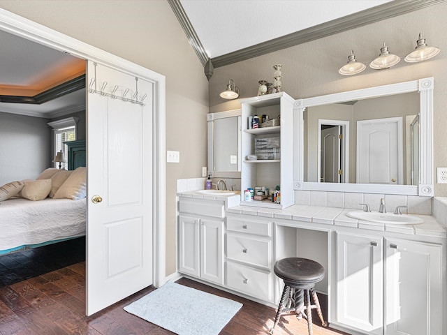 bathroom with wood-type flooring, vanity, vaulted ceiling, and ornamental molding