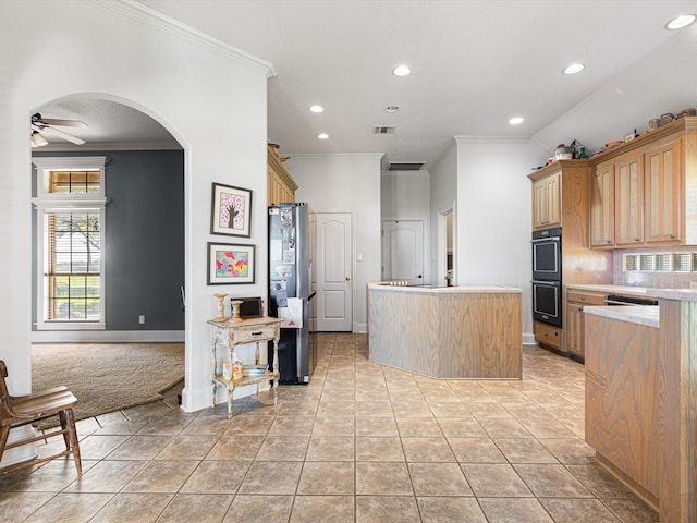 kitchen with ornamental molding, ceiling fan, light tile patterned floors, a center island, and stainless steel refrigerator