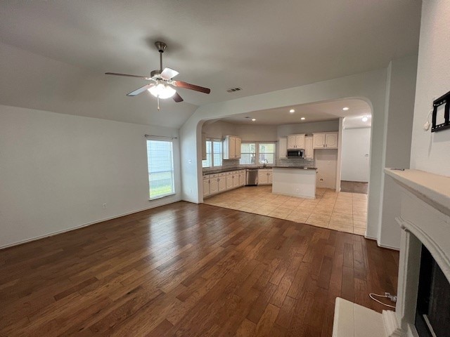 unfurnished living room with vaulted ceiling, light hardwood / wood-style floors, and ceiling fan