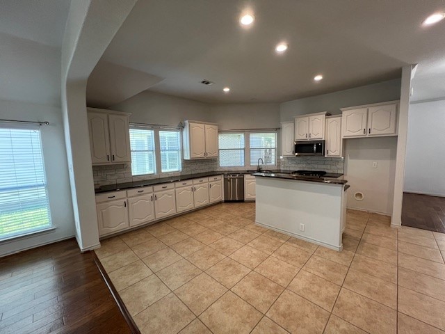 kitchen with light hardwood / wood-style floors, appliances with stainless steel finishes, decorative backsplash, and white cabinets