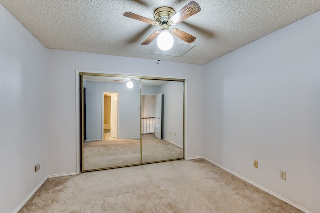 unfurnished bedroom featuring ceiling fan, light colored carpet, a textured ceiling, and a closet