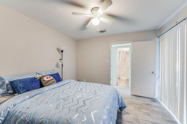 bedroom with ceiling fan, light hardwood / wood-style floors, and a textured ceiling