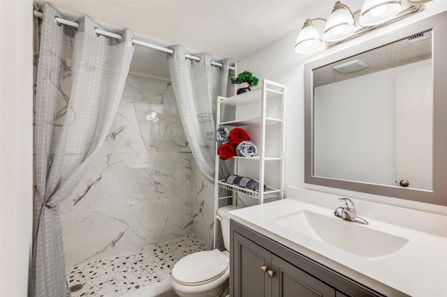 bathroom featuring toilet, a tile shower, a textured ceiling, and vanity