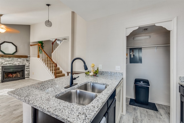 kitchen featuring decorative light fixtures, light stone countertops, sink, and light hardwood / wood-style flooring