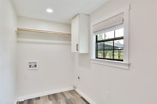 laundry room with hookup for an electric dryer, hookup for a washing machine, light wood-type flooring, and cabinets