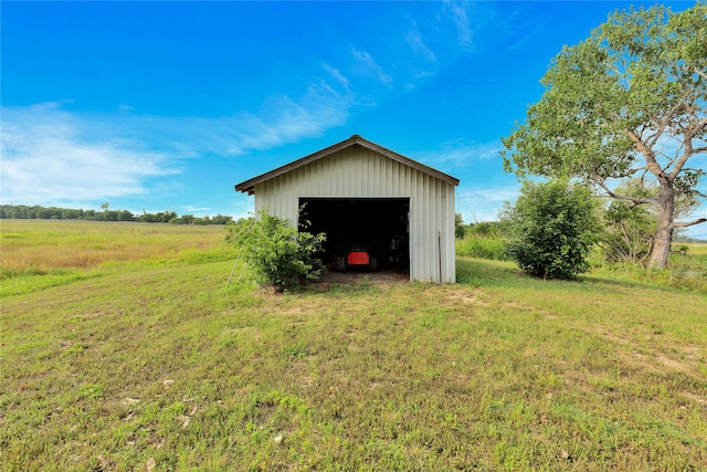 view of outbuilding with a rural view, a garage, and a lawn