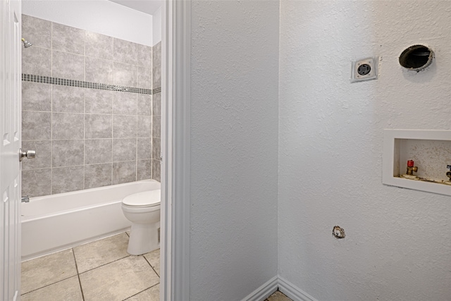 bathroom featuring toilet, tiled shower / bath combo, and tile patterned flooring