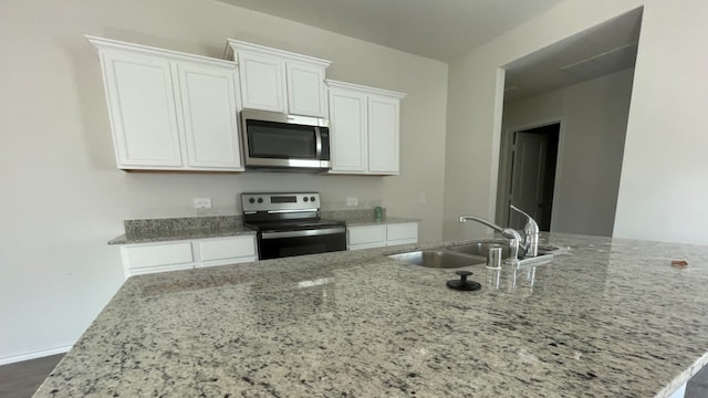 kitchen with white cabinetry, sink, appliances with stainless steel finishes, light stone countertops, and dark wood-type flooring