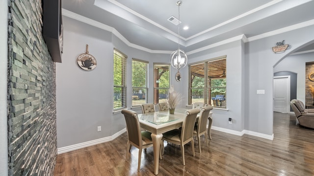 dining area with ornamental molding, dark wood-type flooring, and a raised ceiling