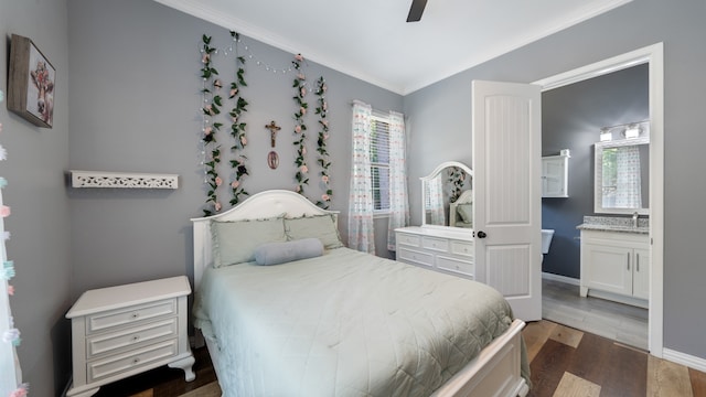 bedroom featuring connected bathroom, dark wood-type flooring, crown molding, and ceiling fan