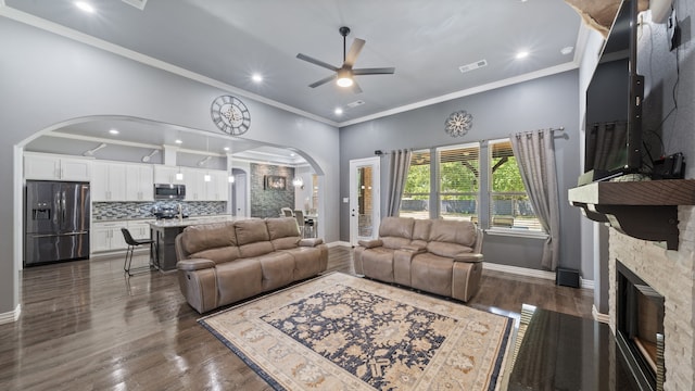 living room featuring ornamental molding, dark wood-type flooring, a fireplace, and ceiling fan