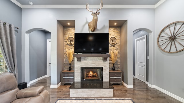 living room featuring ornamental molding, a stone fireplace, and dark hardwood / wood-style flooring