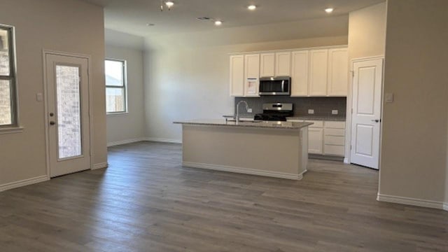 kitchen featuring sink, stainless steel appliances, white cabinetry, and a center island with sink