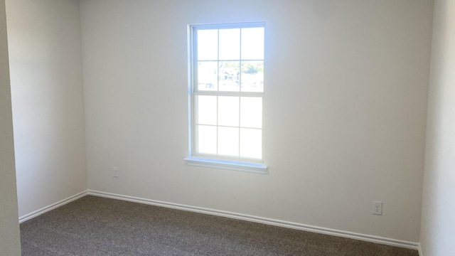 spare room featuring dark carpet