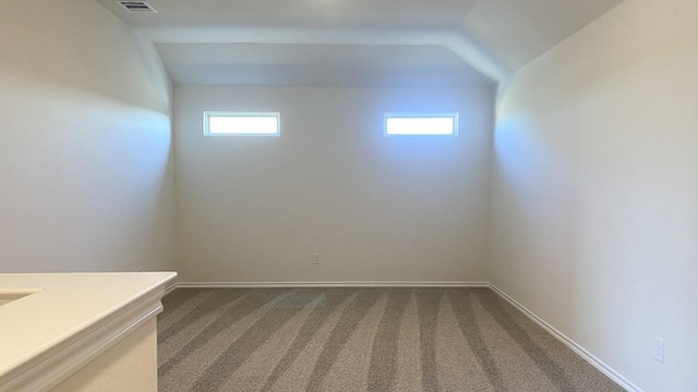 carpeted spare room with plenty of natural light and vaulted ceiling