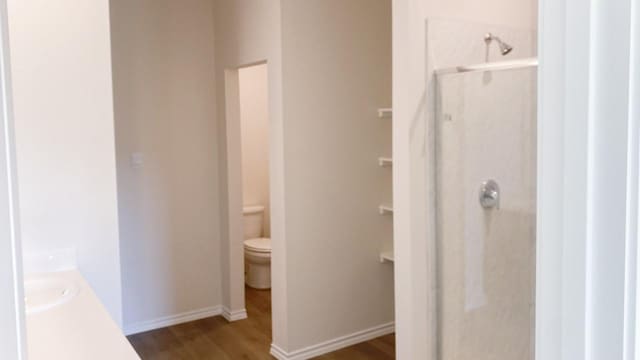 bathroom featuring a shower, hardwood / wood-style floors, vanity, and toilet