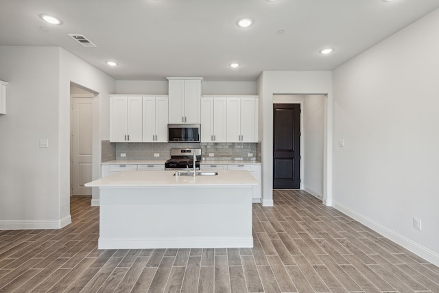 kitchen featuring a kitchen island with sink, white cabinets, stainless steel appliances, and light wood-type flooring