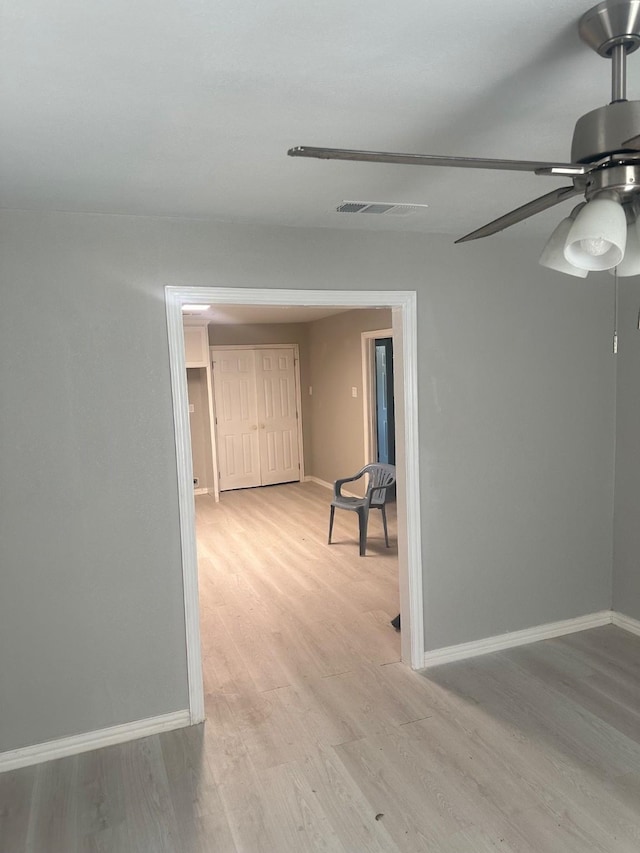 unfurnished room with baseboards, visible vents, ceiling fan, and light wood finished floors