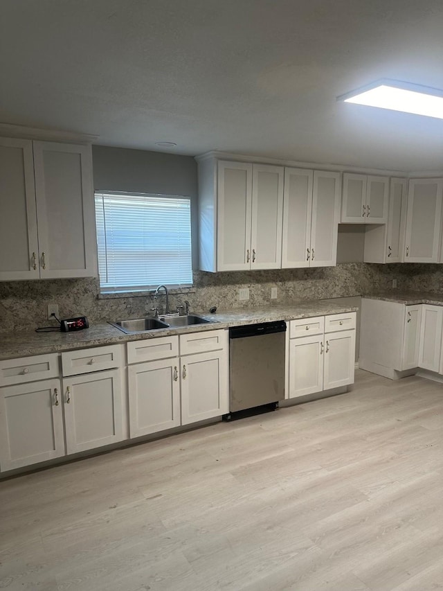 kitchen featuring stainless steel dishwasher, a sink, decorative backsplash, and light wood-style flooring
