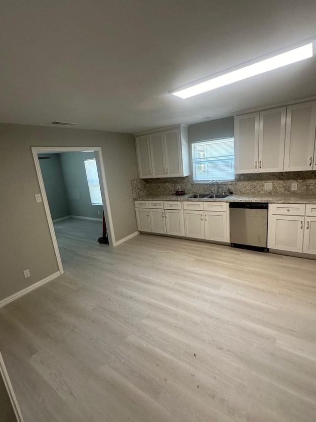 kitchen with decorative backsplash, stainless steel dishwasher, a sink, baseboards, and light wood-style flooring