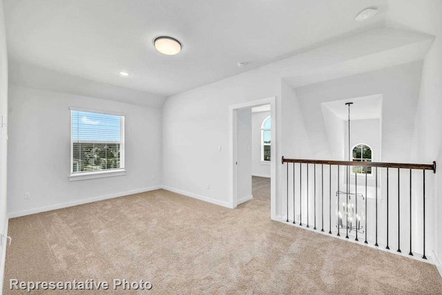 spare room featuring a notable chandelier and light colored carpet