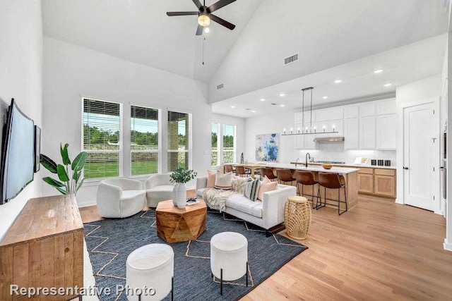 living room featuring light hardwood / wood-style floors, high vaulted ceiling, and ceiling fan