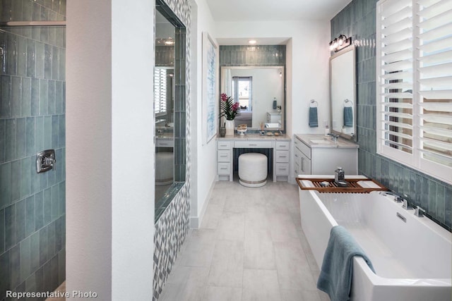 bathroom with a bathing tub, vanity, and tile walls