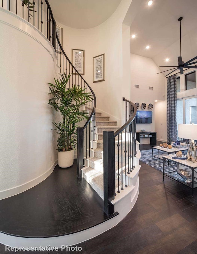 stairway with hardwood / wood-style flooring and high vaulted ceiling