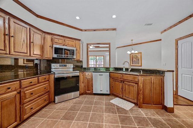 kitchen featuring appliances with stainless steel finishes, a chandelier, ornamental molding, pendant lighting, and sink