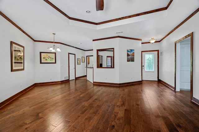 unfurnished living room featuring a raised ceiling, ornamental molding, dark hardwood / wood-style flooring, and a chandelier